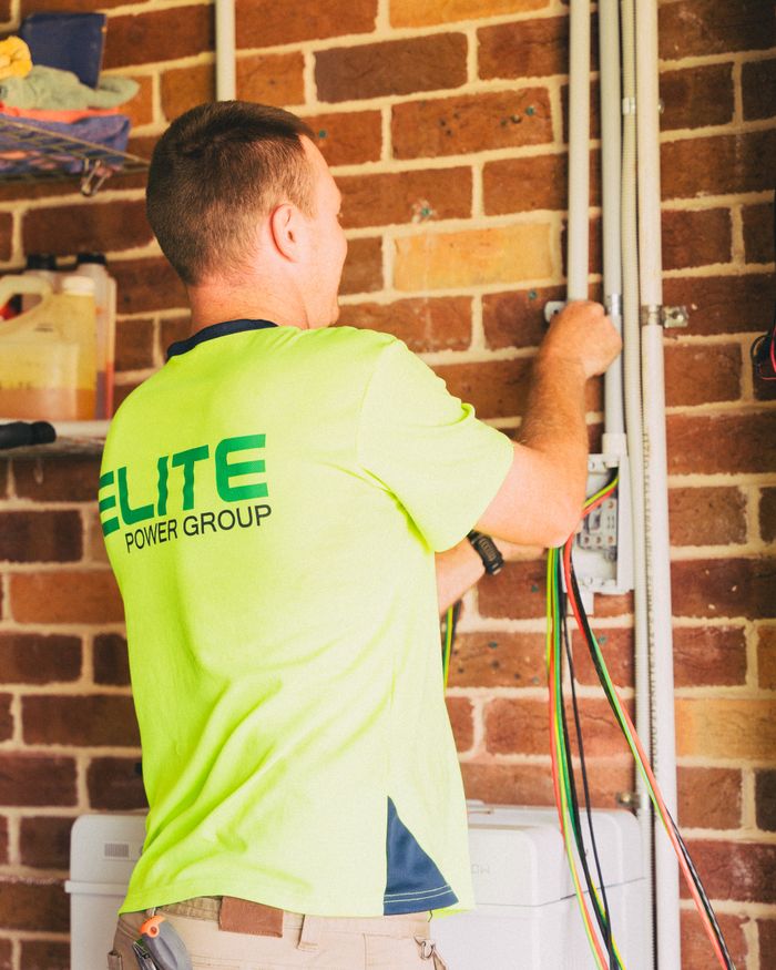 Electrical technician working on cabling installation in home setting, focusing on energy management.