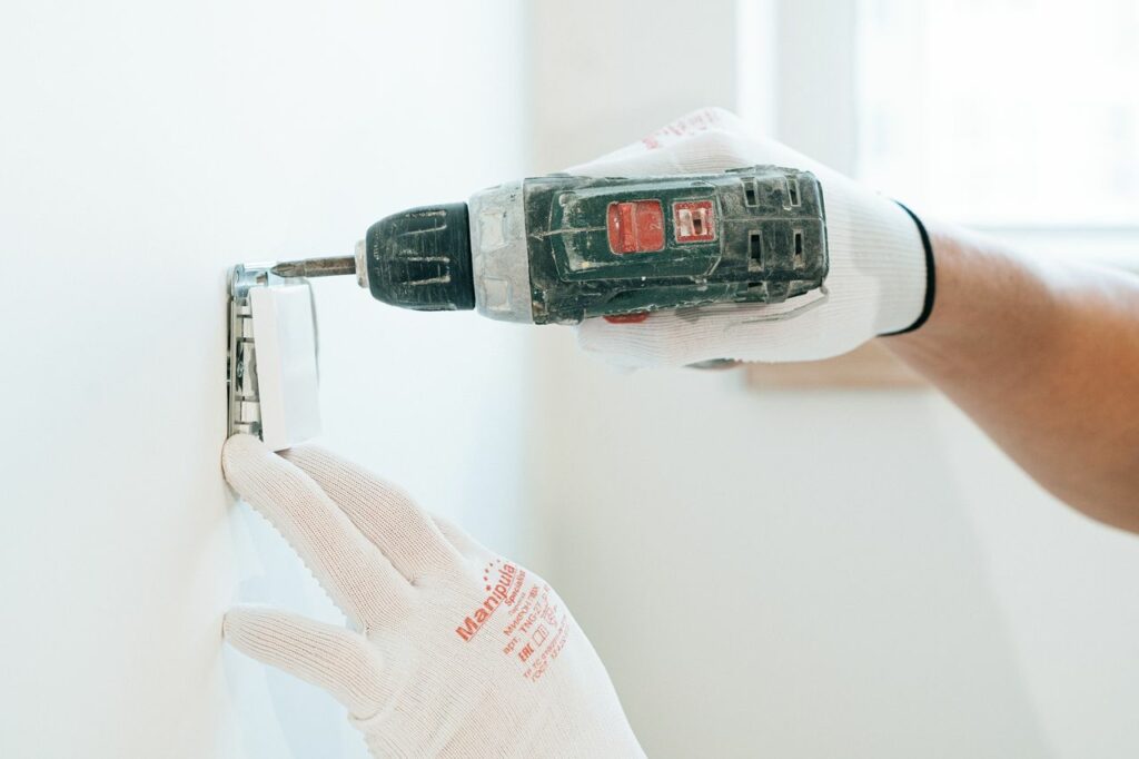 Crafting Captivating Headlines: Your awesome post title goes here Gloved hands using a drill to install a power outlet on a wall, focusing on precision and safety.